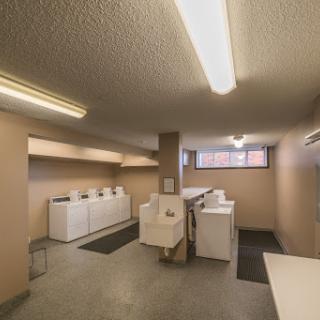 A spacious and well-lit laundry room featuring modern washing machines and dryers.