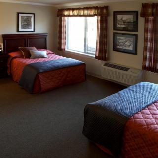 A cozy hotel room with twin beds and a window letting in natural light.