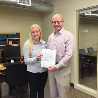 Two people holding a document in an office setting.