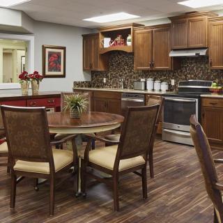 A cozy kitchen and dining area featuring wooden cabinets, a round table with chairs, and modern appliances.