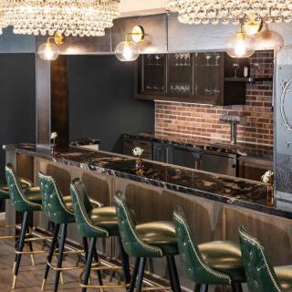 A stylish bar interior featuring green chairs and elegant lighting fixtures.
