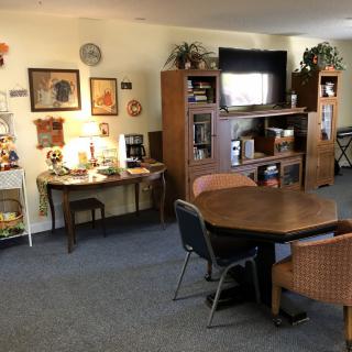 A cozy living room with a table and chairs, an entertainment center with a television, and various decorations.