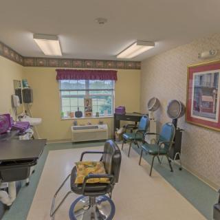 A small hair salon with chairs and dryers inside a well-lit room.