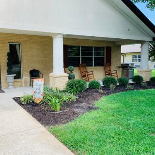 A welcoming porch with rocking chairs and beautifully landscaped greenery.