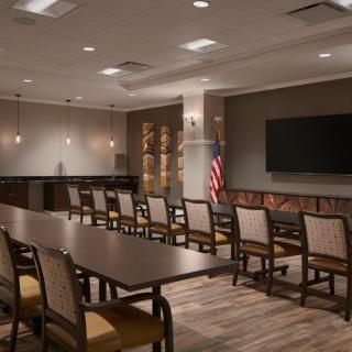 A modern conference room with a large table, chairs, and a television on the wall.