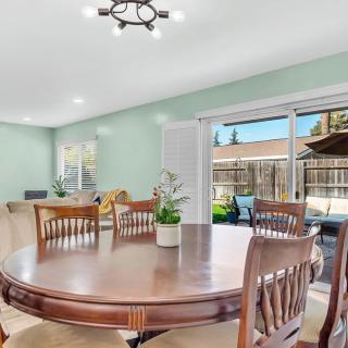 A spacious dining room with a wooden table and chairs, featuring a view through sliding glass doors to the outdoors.