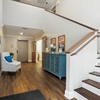 A beautifully designed foyer featuring a wooden staircase, blue storage cabinet, and cozy armchair.