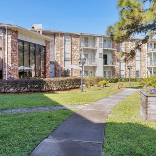A residential apartment building with well-maintained gardens and a paved pathway.