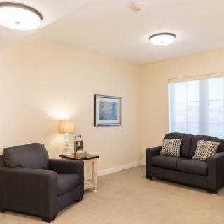 A cozy living room with a sofa, armchair, and a warm lamp.