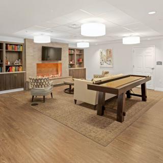 A modern living room with a shuffleboard table, cozy seating, and built-in bookshelves surrounding a fireplace.