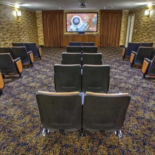 A small theater with arranged seating and a large screen at the front.