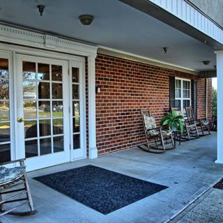 A welcoming porch featuring rocking chairs and a brick exterior.