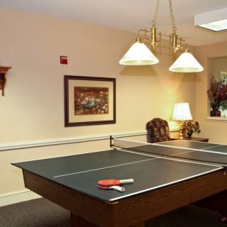 A cozy indoor game room featuring a ping pong table and warm lighting.