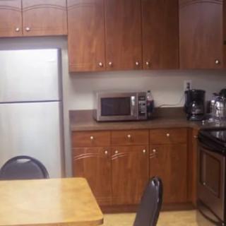 A kitchen with wooden cabinets, appliances, and a dining area.