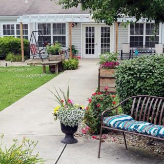A serene garden patio with a bench, flowers, and a swing.