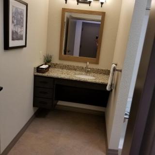 A bathroom with a modern vanity and mirror, featuring stylish lighting and decor.
