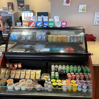 A refrigerated display case filled with assorted snacks and drinks in a cafe or store setting.