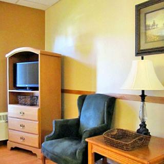 A cozy room with an armchair, television, lamp, and a side table.