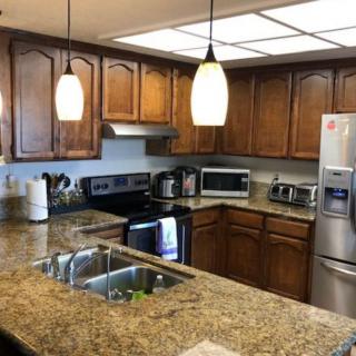 A modern kitchen with granite countertops and wooden cabinets, equipped with various appliances.