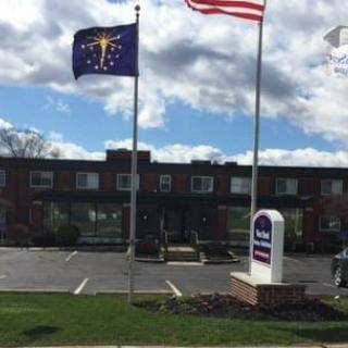 A building with flags and a parking lot under a cloudy sky.