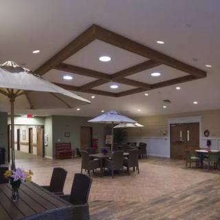 A spacious lobby area with tables, chairs, and decorative umbrellas under soft lighting.