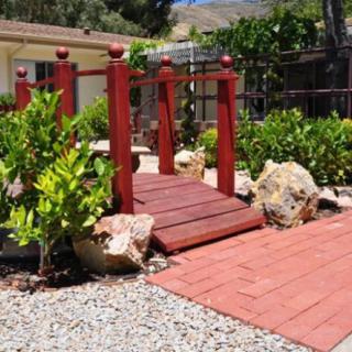 A picturesque garden view featuring a small wooden bridge surrounded by lush greenery and rocks.