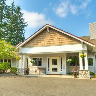A charming residential building with a well-maintained exterior, surrounded by greenery and set against a blue sky.