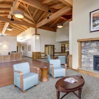 A cozy lobby with modern furniture and a fireplace, featuring wooden beams and an inviting seating area.