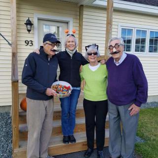 A group of four people in playful costumes standing outside a house.