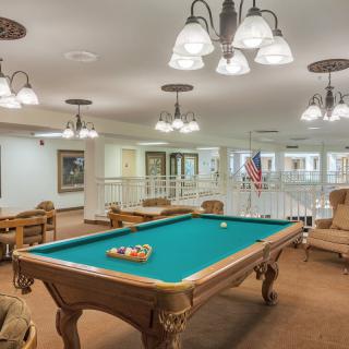 A well-lit game room featuring a classic pool table surrounded by comfortable seating.