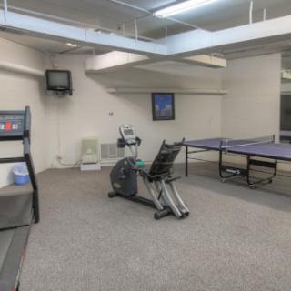 A recreational room featuring an elliptical machine and a ping pong table.