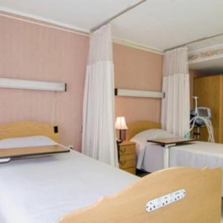A hospital room featuring two beds separated by curtains and equipped with medical apparatus.
