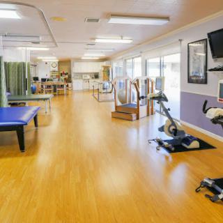 A spacious physical therapy clinic equipped with exercise stations and ample natural light.