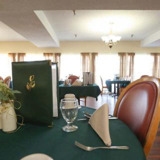 A neatly set dining table in a well-lit restaurant interior, featuring a menu, folded napkin, and glassware.