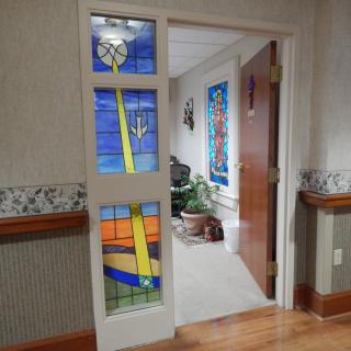 A corridor featuring a door with vibrant stained glass panels.
