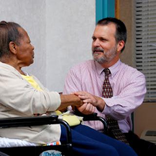 A caregiver engages in a warm conversation with an elderly woman in a wheelchair, showcasing compassion and connection.