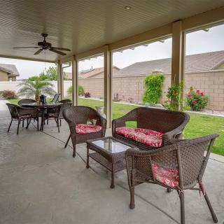 A cozy covered patio with wicker furniture and a view of a neat backyard garden.