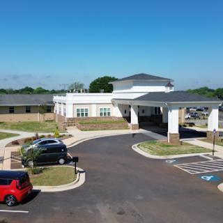 A view of a modern healthcare facility with a spacious parking lot under a clear blue sky.