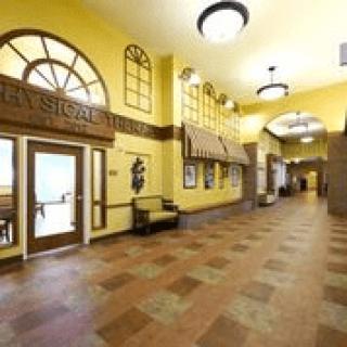 A spacious hallway with arched windows and yellow walls, featuring ceiling lights and decorative elements.