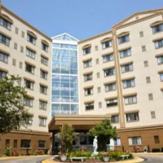 A multi-story hotel building with a central glass atrium and landscaped entrance.