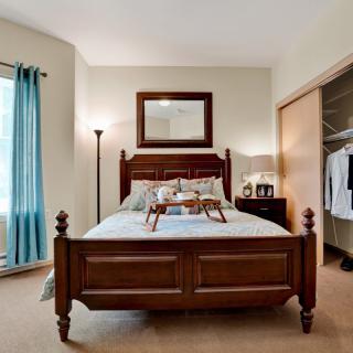 A well-decorated bedroom with a wooden bed, mirror, and closet.