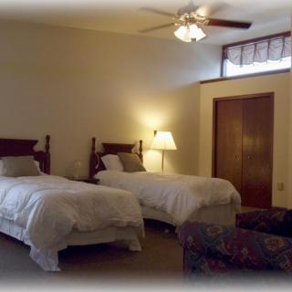 A cozy bedroom with two single beds, a lamp, and a ceiling fan.