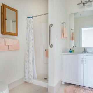A bright and modern bathroom featuring a shower, sink, and neatly arranged towels.