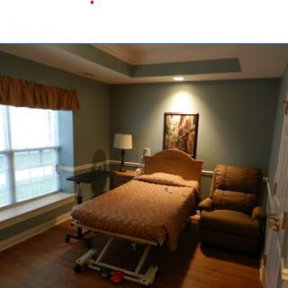 A comfortable hospital room featuring a patient bed, recliner chair, and a view outside.