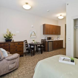A cozy studio apartment featuring a living area with a sofa, a small dining table, and a kitchenette.