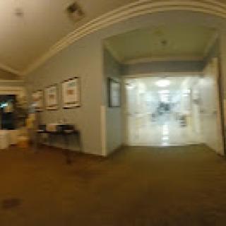 A view of a well-lit hallway with artwork on the walls, leading to a brighter area.
