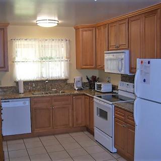 A modern kitchen with wooden cabinets, appliances including a refrigerator, oven, and dishwasher.