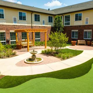 A serene courtyard with a fountain, surrounded by a well-maintained garden and comfortable seating.