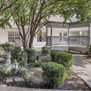A peaceful garden setting with a gazebo and manicured shrubs.
