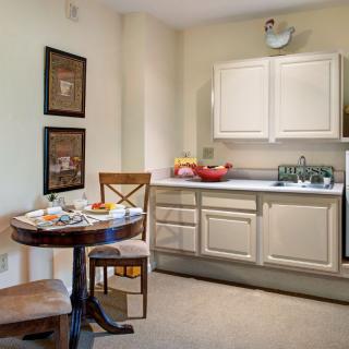A cozy kitchen interior with a small dining table and chairs, featuring white cabinets and modern appliances.
